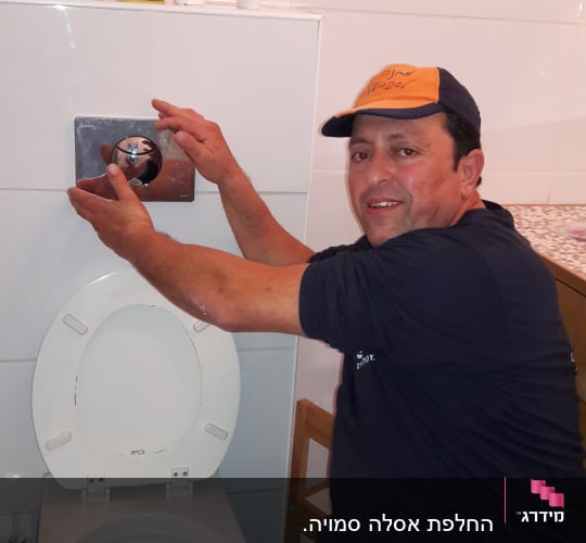 אדם מתקין לחצן ניאגרה בשירותים